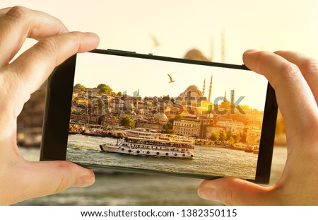 Istanbul in mobile phone photograph, Turkey. Tourist takes picture of sunny Istanbul. Eastern landscape photo on smartphone screen. Concept of photography, travel, tourism, Bosphorus and vacation.