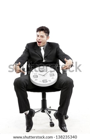 Portrait of a businessman sitting and put a clock between his leg against white background