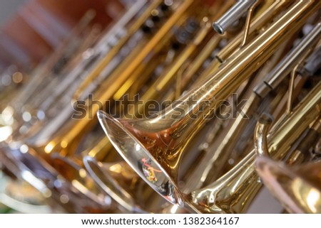 A hanging line of brass instruments from trumpet to trombone with missing parts used for repair accessories at a music store. Royalty-Free Stock Photo #1382364167
