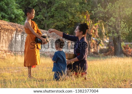 Buddhist elder Novice. The family Children woman putting food offerings in a monk's alms bowl and a woman prostrating oneself to respect worship monks, monks walking routine every morning.