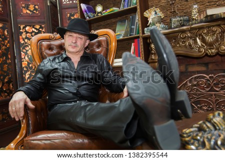 Elderly man in a hat in a leather chair