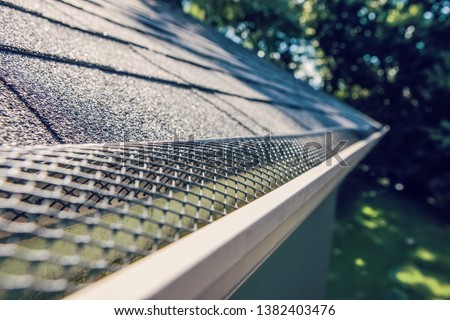 Plastic guard over gutter trough on a roof  Royalty-Free Stock Photo #1382403476