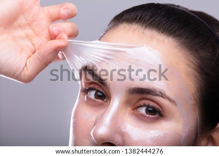 Portrait Of A Beautiful Young Woman Removing Peeling Mask From Her Face
