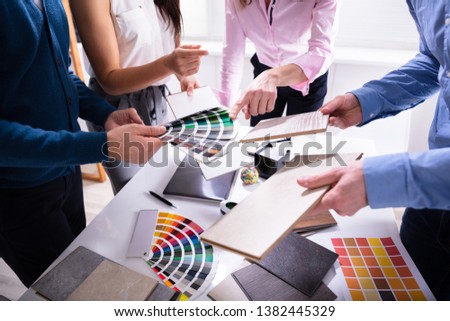 Businesspeople's Hand Choosing Color From Various Color Swatches In Office