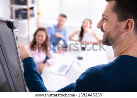 Close-up Of Young Businessman Giving Presentation To His Coworker In Office