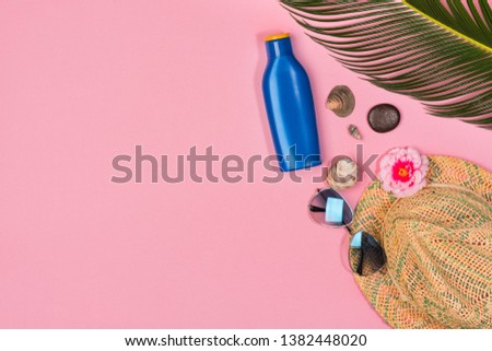 sunblock, glasses, hat on a pink background, top view.