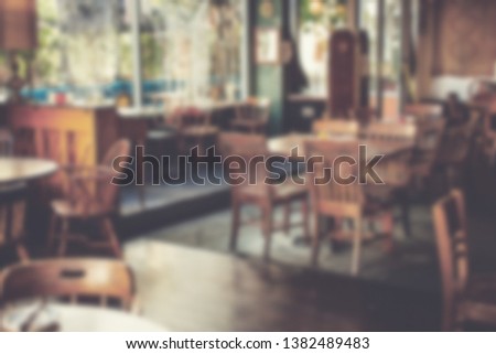 A blurry background of a restaurant scene featuring tables, chairs and windows