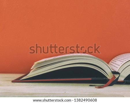 Red background book. Photo of half of open book on wooden table. Book with red and black bookmarks. Photo of book with copy space. Back to school. Education background.