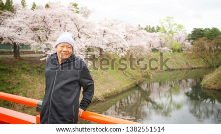A happy man in black jacket with beautiful full blooming cherry blossom background in spring time of Japan 