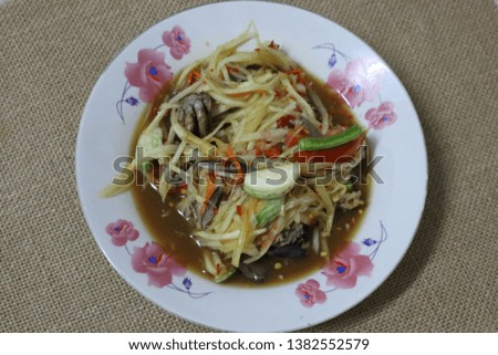 Close-up pictures of papaya salad, crab, chili, garlic, lentils, tomatoes in a plate