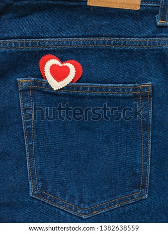 Red and white heart in the pocket of bright blue jeans.