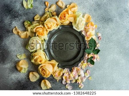 Festive table setting with beautiful roses, modern plates and cutlery on rustic grey background with copy space