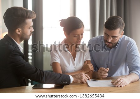 Millennial couple take mortgage or loan together, signing document or contract at lawyer, husband and wife in realtor office put signature on document finalize buying house. Ownership concept Royalty-Free Stock Photo #1382655434