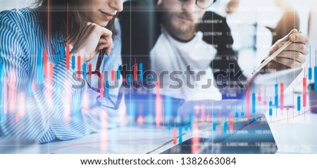 Business woman and her collegues sitting front laptop computer with financial graphs and statistics on monitor. Double exposure