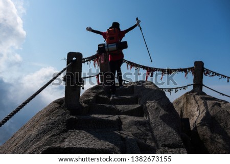 A young women climber standing on the Top of the Celestial Capital Peak (also known as Tian Du Feng, or Capital of Heaven Peak) in Mountain Huang, Anhui Province, China