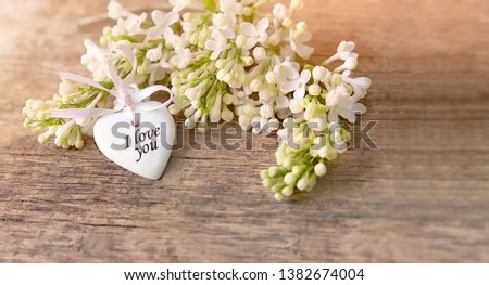 White lilac flowers and heart decor with text "I love you" on wooden background close up. romantic Greeting card. spring season