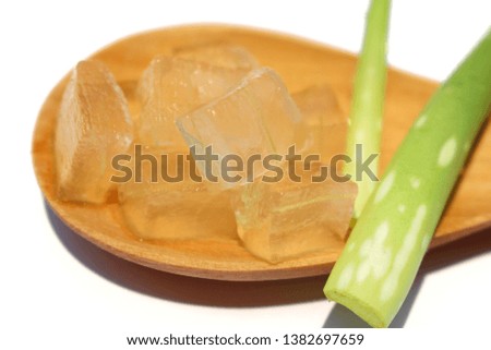 The herb is jelly in a brown wooden spoon on a white background, aloe vera