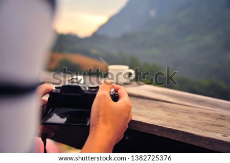 Close Up of People Taking Photo of Coffee Cup on The Wooden Table with Mountain Background
