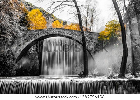 Long exposure of on old traditional Greek stone bridge with waterfalls in natural surrounding