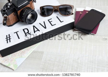 travel and vacation concept - passports, camera, smart phone and lightbox with word travel over wooden table background