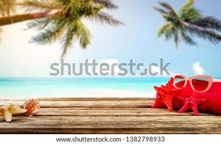 Wooden old desk of free space for your decoration. Summer towel and landscape of beach with palms. Summer suny day. 