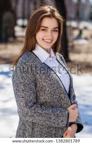 Close up. Young beautiful brunette girl in gray coat posing on spring park