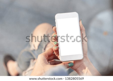Mockup image of woman's hand holding using white mobile phone at outdoor with copy space,blank screen for text.concept for business,people communication,technology electronic device. modern lifestyle