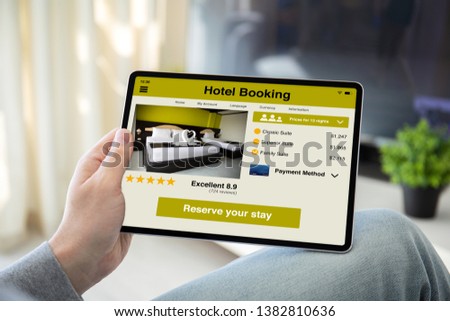 man hands holding computer tablet with app hotel booking on the screen in the home room