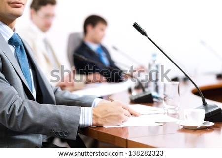 Businessman writing on paper notes, to communicate with colleagues in the background