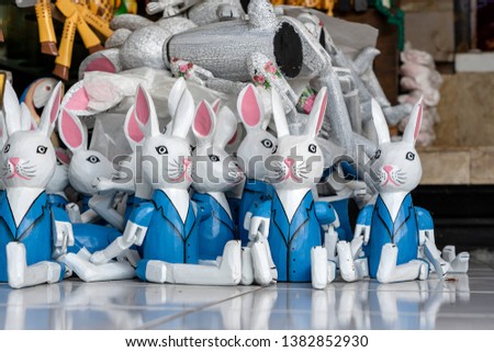 Sale of souvenirs - funny handmade wooden hares in street market. Bright colorful children toys and decoration for interior. Ubud, Bali island, Indonesia. Close up