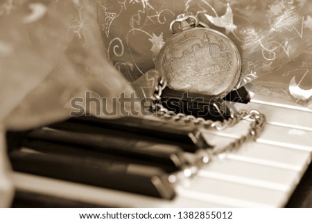 tribute to Ansel Adams, bodegon, photography of Artistic still life in sepia color of piano keys with old Silver chain watch with engraved lid with an old steam locomotive