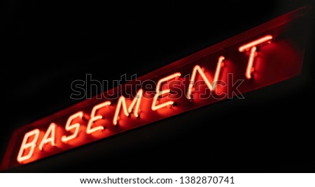 Red neon basement sign on a black background