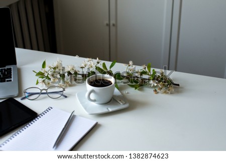 Home office desk in white colors with laptop, cup of coffee, notebook, phone, glasses on a white background. Business womans workplace and objects. Horizontal view. Copy space for text