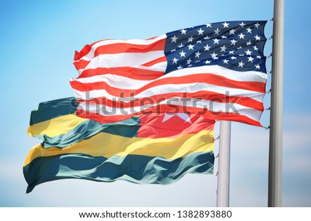 Flags of the USA and Togo against the background of the blue sky