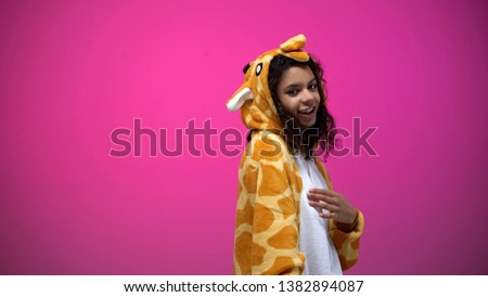 African american lady in funny giraffe costume posing on pink background, fun