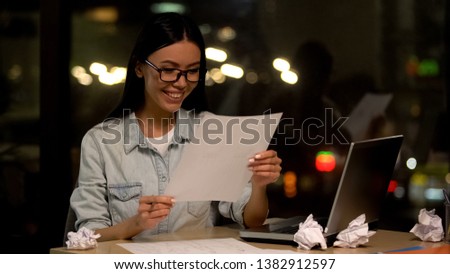 Female designer satisfied with sketch holding paper and smiling, creativity