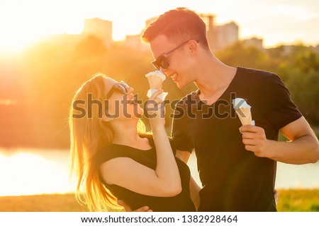happy californian couple in love in summer park. beautiful woman and handsome man eat ice cream in a waffle horn cone at sunset on the beach. cool photosession photoshoot of young family Royalty-Free Stock Photo #1382928464