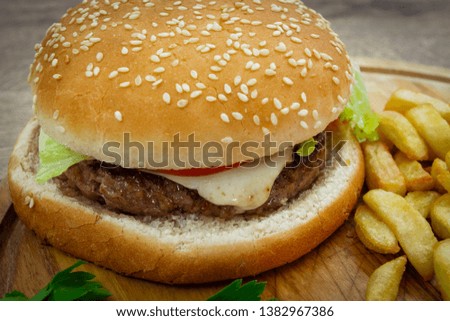 hamburger with fries on wooden board