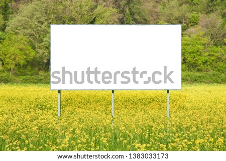 Blank commercial advertising billboard immersed in a rural scene against a yellow flowery field - image with copy space