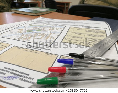 The card lies on the table on her long lanaka, red pen, green pen, blue pen. In the background notebook.
