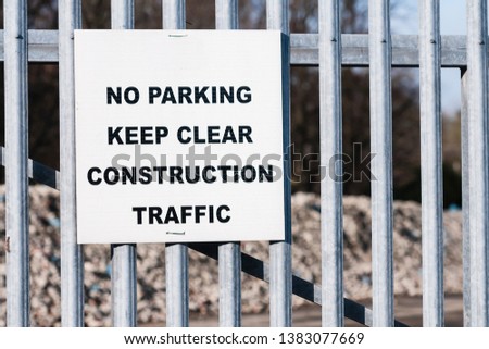 Sign warning public not to park at a gate as it is needed to be kept clear for construction traffic.