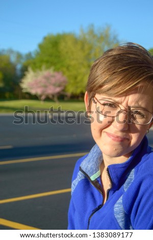 Woman in blue shirt squinting in the sunlight