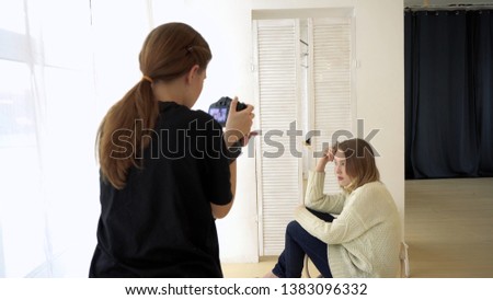 Photographer takes model sitting on chair. Media. Model is romantically placed on chair near window of gentle light, working with professional photographer