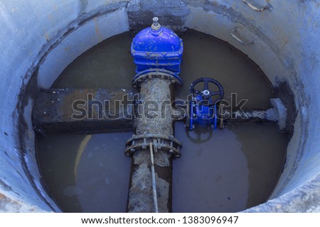 Pipeline elements, plastic pipes, cast-iron valve in a concrete well. There is a concrete stop on the pipe.Close up