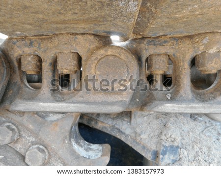 Detailed image of gear and belt chain from a piece of heavy equipment being used in a sandy environment.       