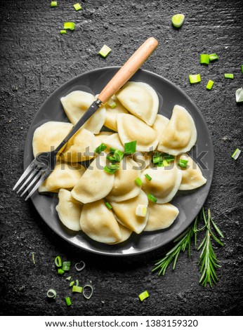 Dumplings with chopped green onions and rosemary. On black rustic background