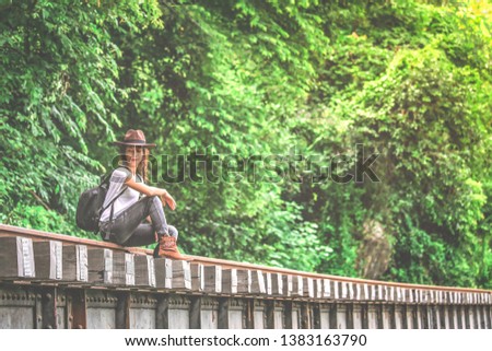 Beautiful Asian girl in casual wear with cowgirl hat sitting on rail, adventure and outdoor concept