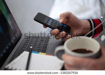 Calculator on smartphone in hands of businessman, close-up over keyboard of laptop.