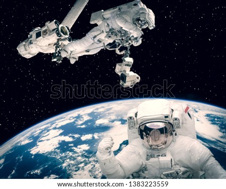Astronaut waving. Other astronaut on the backdrop. Space scene. The elements of this image furnished by NASA.
