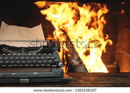 Typewriter with blank paper page on a writer desk on a burning fire background.